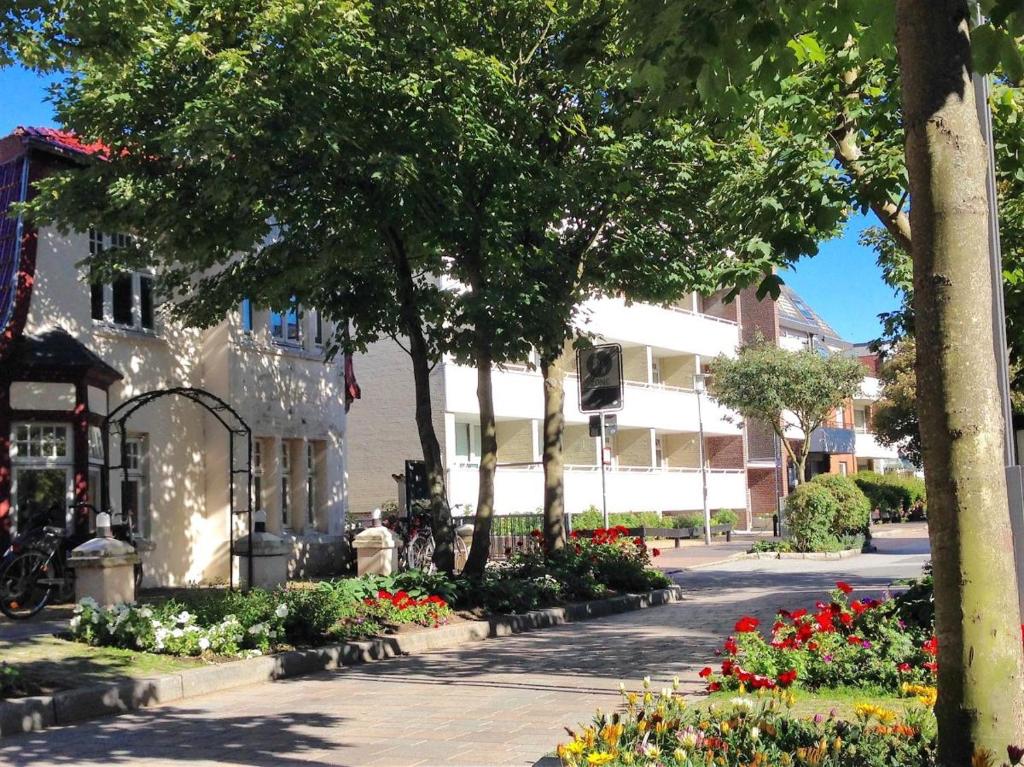 un parc avec des fleurs, un bâtiment et des arbres dans l'établissement Spalthoff 18, à Westerland