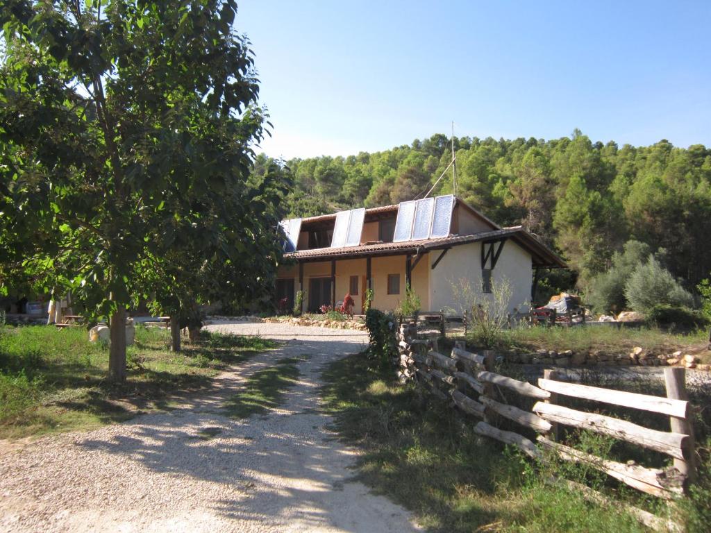 une maison avec une clôture à côté d'un chemin de terre dans l'établissement Mas la Llum, la casa de palla, à Arens de Lledó