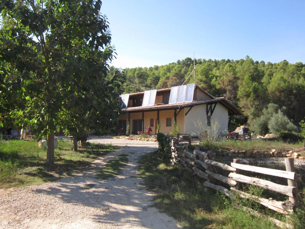 a house with a fence next to a dirt road at Mas la Llum, la casa de palla in Arens de Lledó