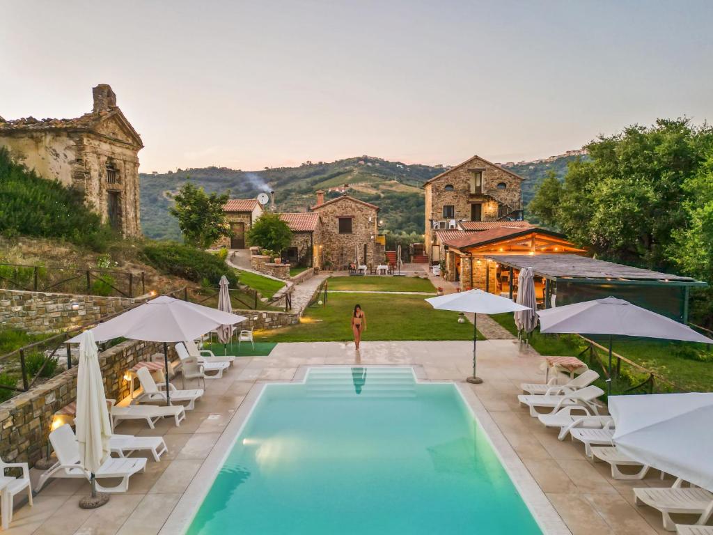 una piscina al aire libre con sillas y sombrillas junto a una casa en Le Querce Farmhouse, en Agropoli