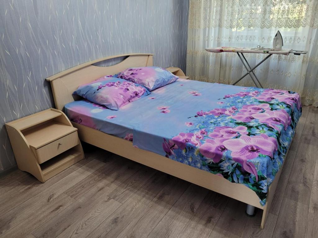 een slaapkamer met een bed met een bloemdekbed bij Апартаменты Гоголя 46 in Karagandy