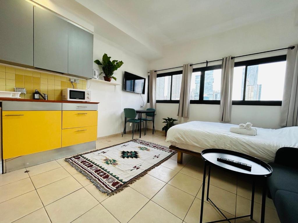 a bedroom with a bed and a kitchen with yellow cabinets at Lev Florentin Apartments - Montefiore TLV in Tel Aviv