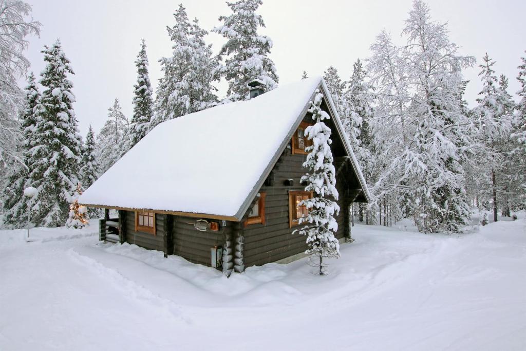 una cabaña en el bosque cubierta de nieve en Saremökki en Kittilä