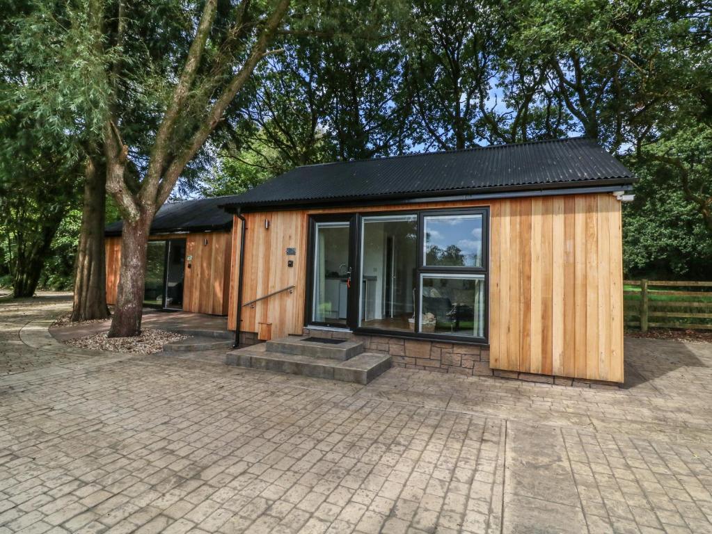 a small wooden house with windows and a tree at Jasmine in Barnstaple