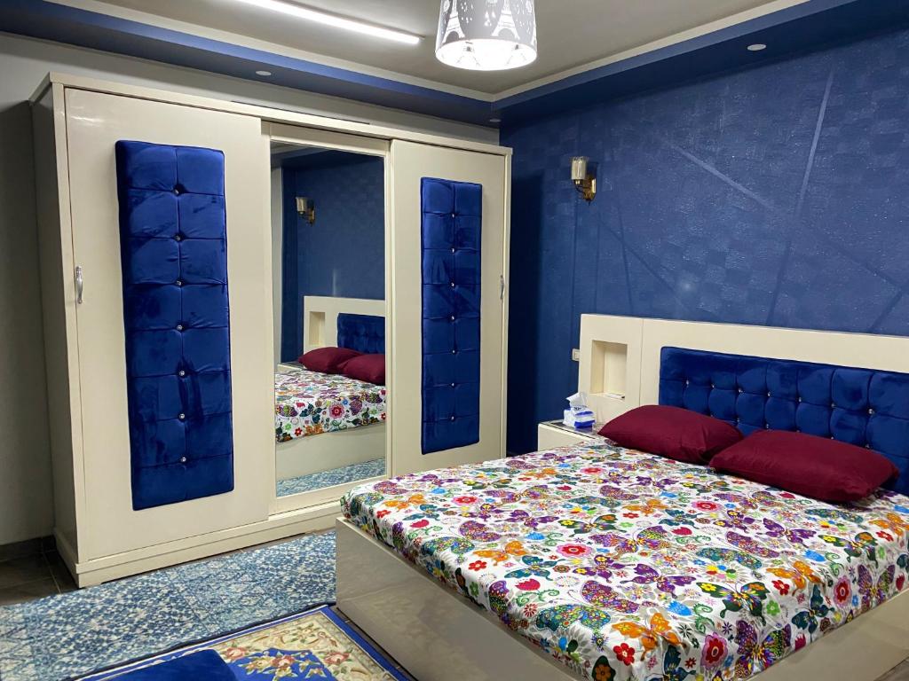 a bedroom with blue walls and a bed and mirrors at Assuit ultra modern apartment in Asyut