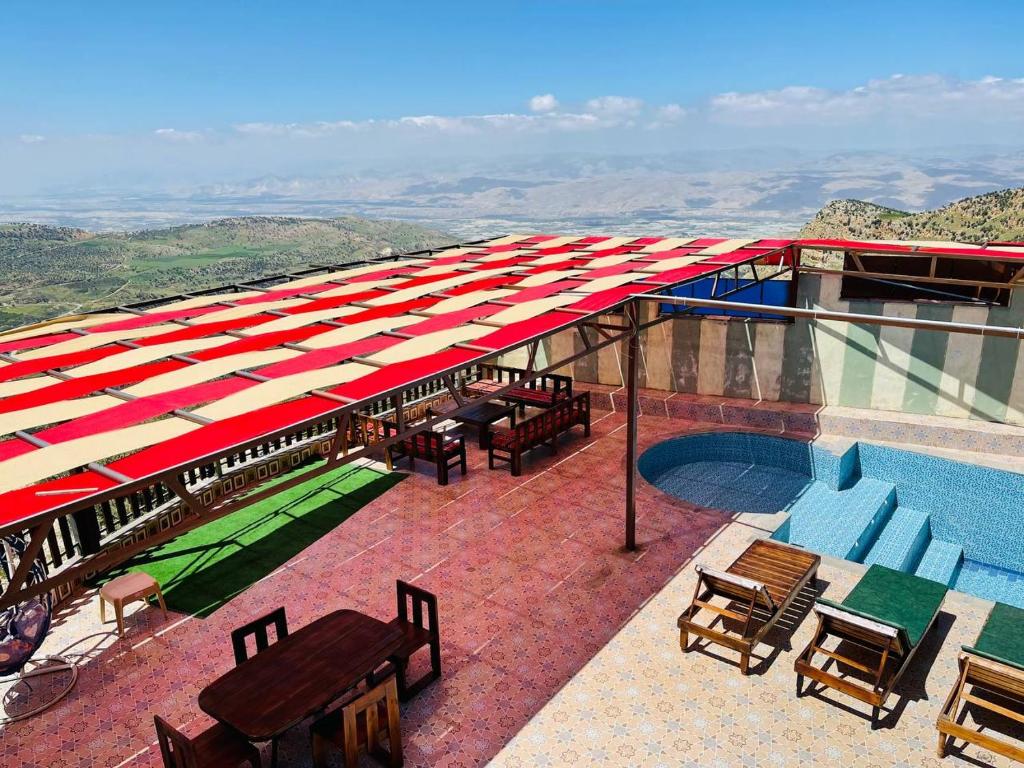 a rooftop patio with a pool and tables and chairs at منتجع وشالية السفينة الريفي in Ajloun