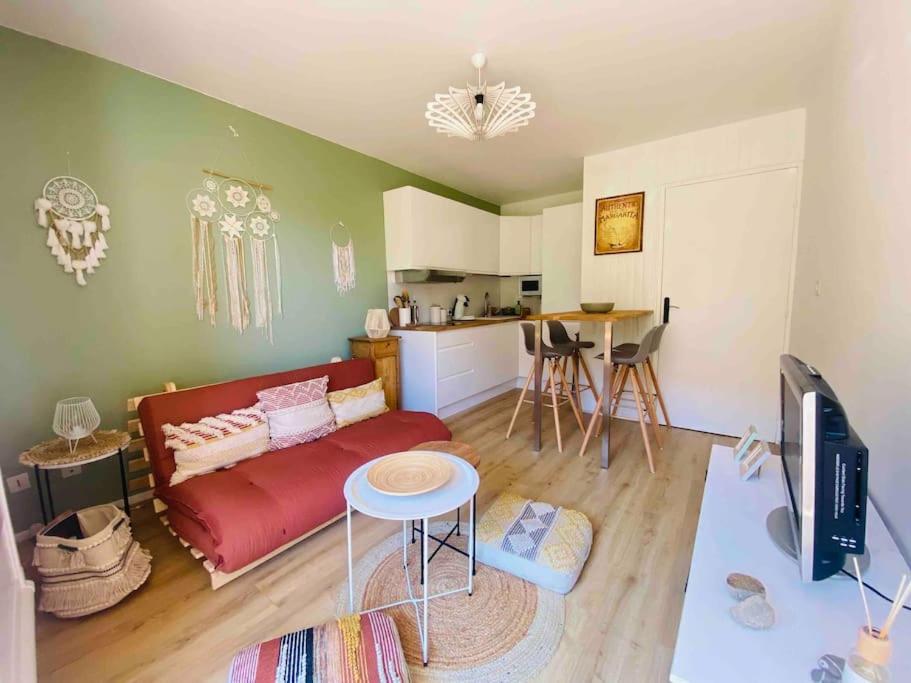 un salon avec un canapé rouge et une cuisine dans l'établissement Appartement à la Favière T2 à 5 minutes à pied de la plage, à Bormes-les-Mimosas