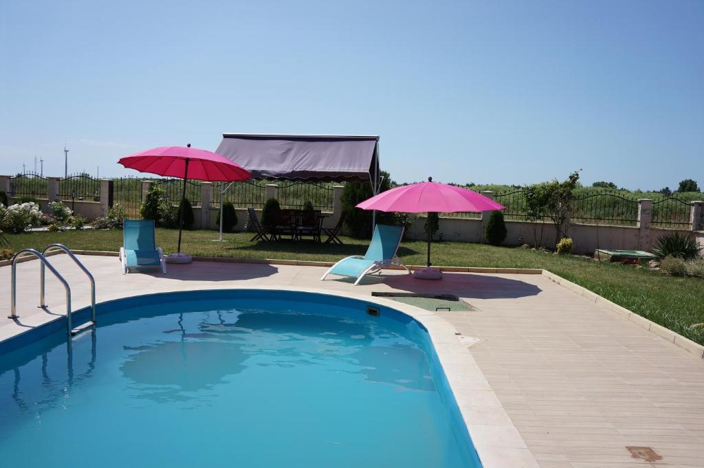 a swimming pool with two umbrellas and two chairs at Guest House Golden Flake 4km from Bolata beach in Bŭlgarevo