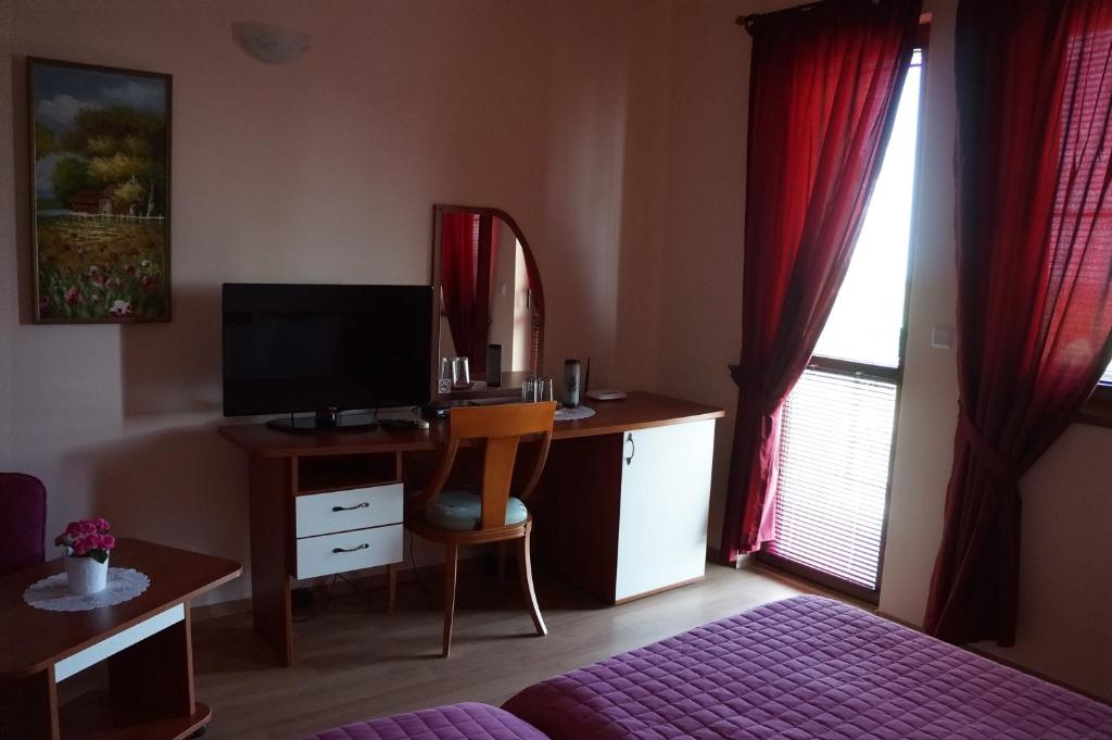 a bedroom with a bed and a desk with a television at Guest House Golden Flake 4km from Bolata beach in Bŭlgarevo