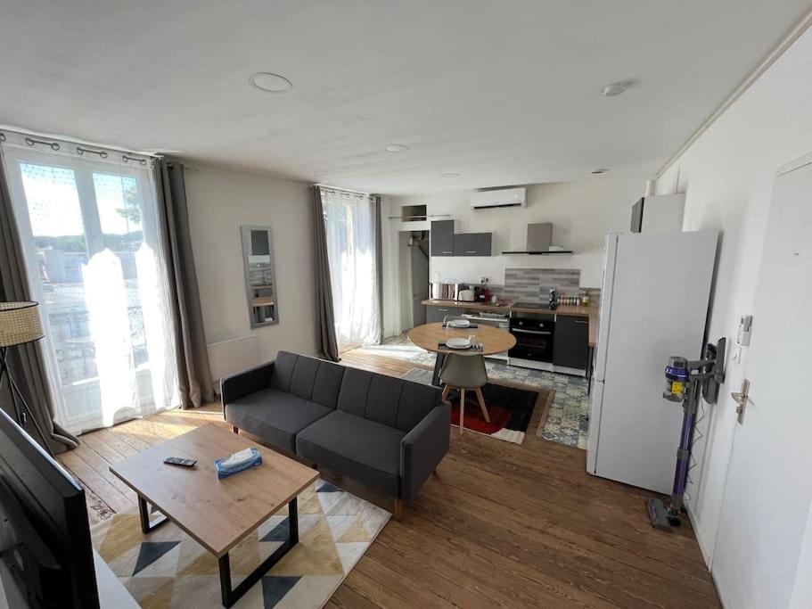 un salon avec un canapé noir et une cuisine dans l&#39;établissement Charmant appartement avec balcon proche du centre., à Périgueux