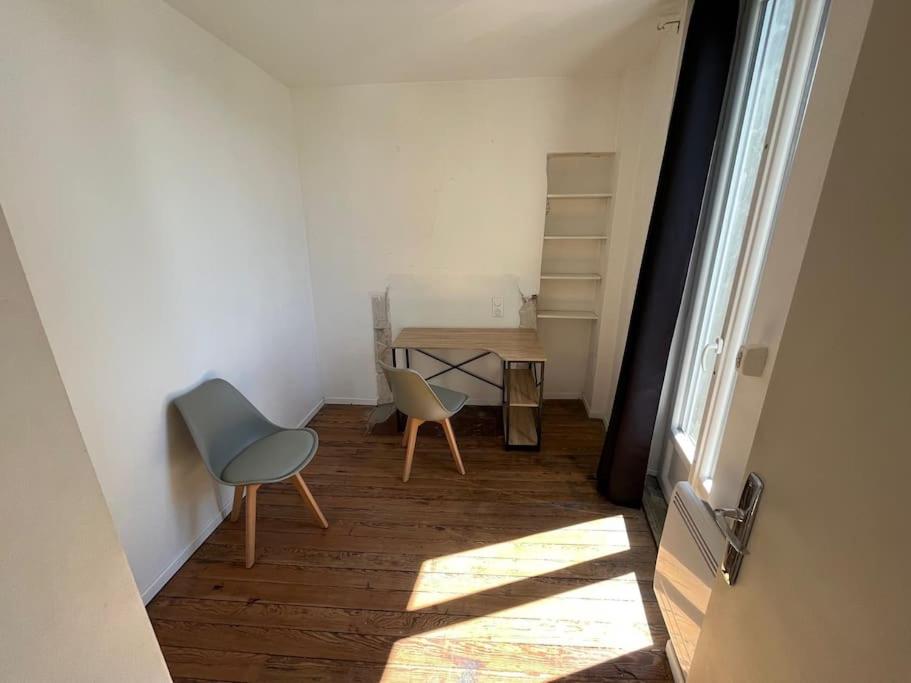 - un couloir avec deux chaises et une table dans une chambre dans l&#39;établissement Charmant appartement avec balcon proche du centre., à Périgueux