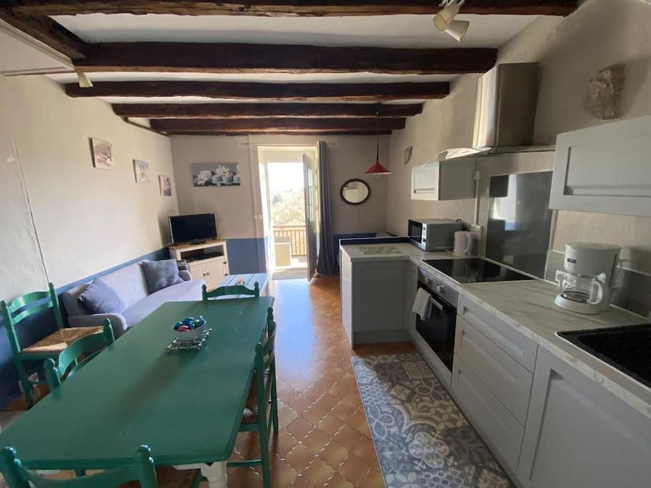 a kitchen with a green table and a living room at La Marguerite sur Gartempe in Châteauponsac