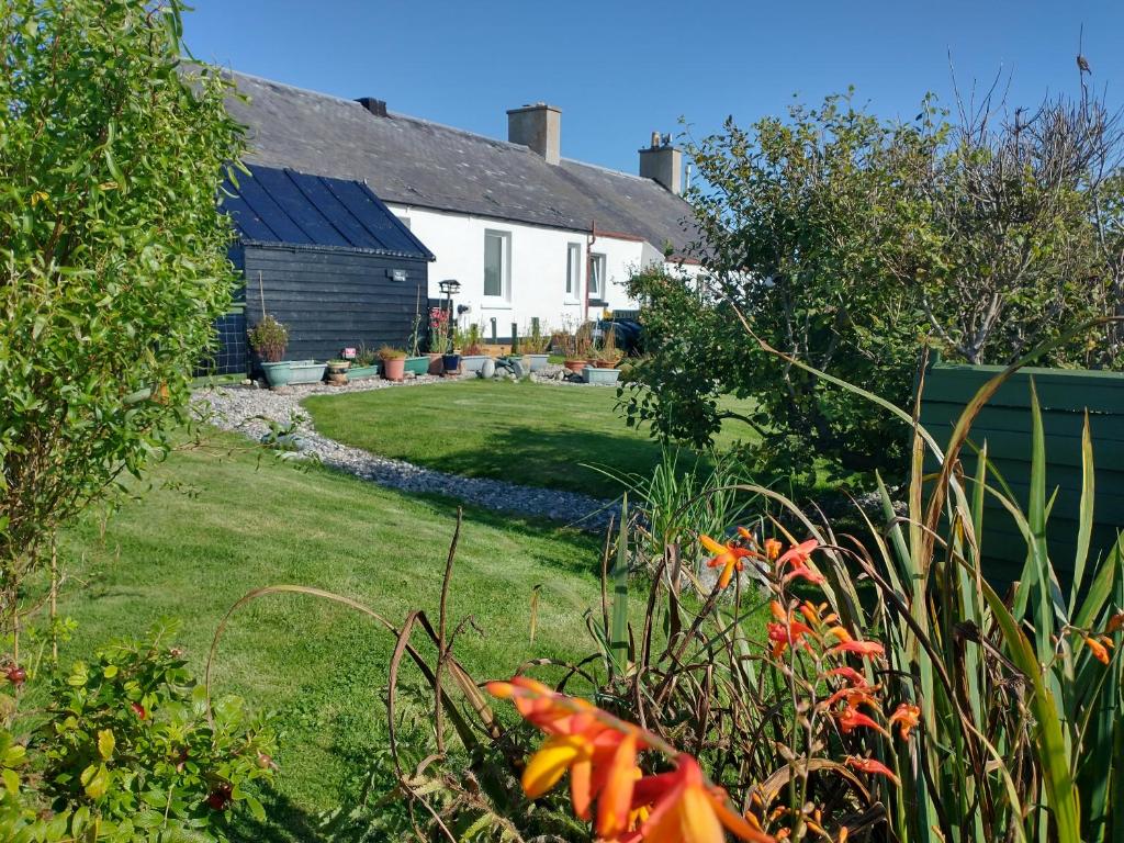 a house with a yard with flowers in front of it at Snowberry Cottage in Borve