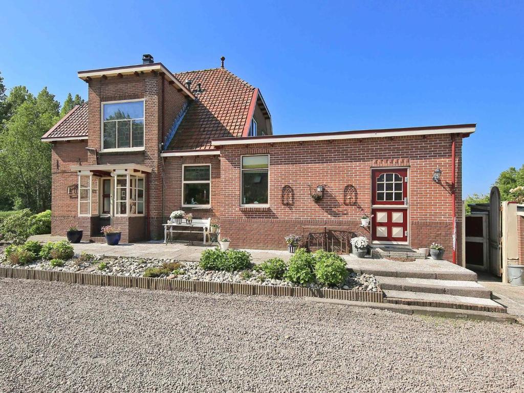 een bakstenen huis met een rode deur en een patio bij Characteristic country house with wellness in Lijnden