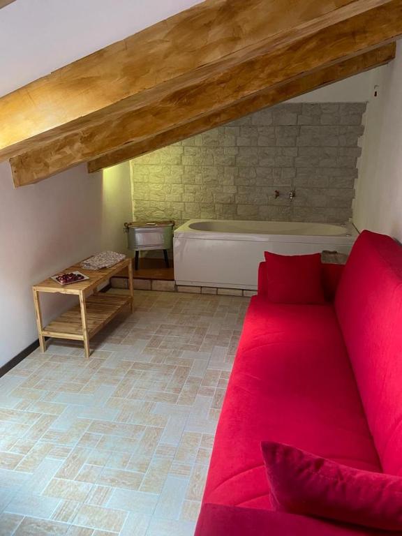 un soggiorno con divano rosso e vasca da bagno di Tulipipì a Sant'Albino