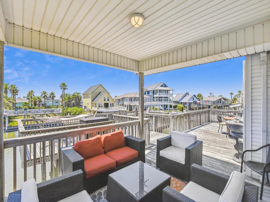 a patio with a couch and chairs on a balcony with a view at Tiki Lagoon in Galveston