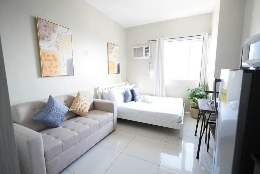 a white living room with a couch and a window at Comfy Studio near Shaw MRT EDSA w/ Wi-Fi & Netflix in Manila