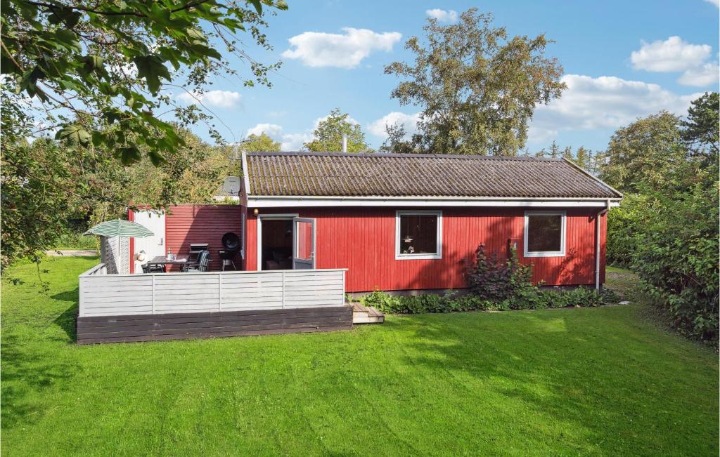 une maison rouge avec une terrasse dans une cour dans l'établissement 2 Bedroom Beautiful Home In Sydals, à Skovby