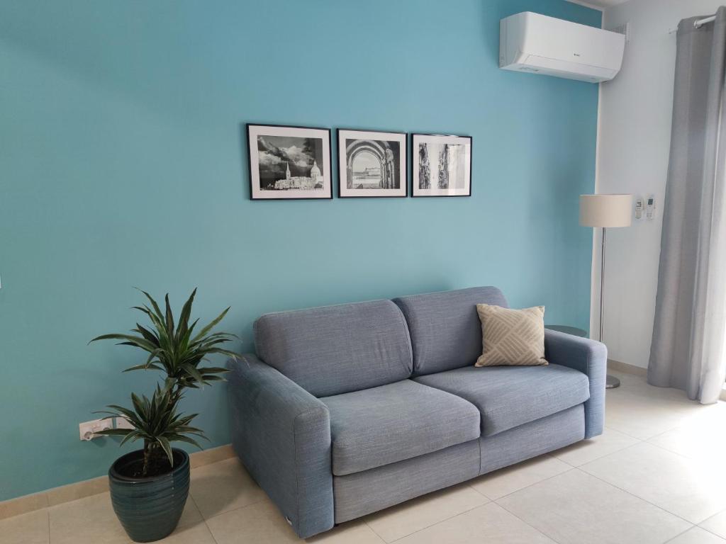 uma sala de estar azul com um sofá e uma planta em Étoile Court Apt - homey, spacious & private patio em Mġarr