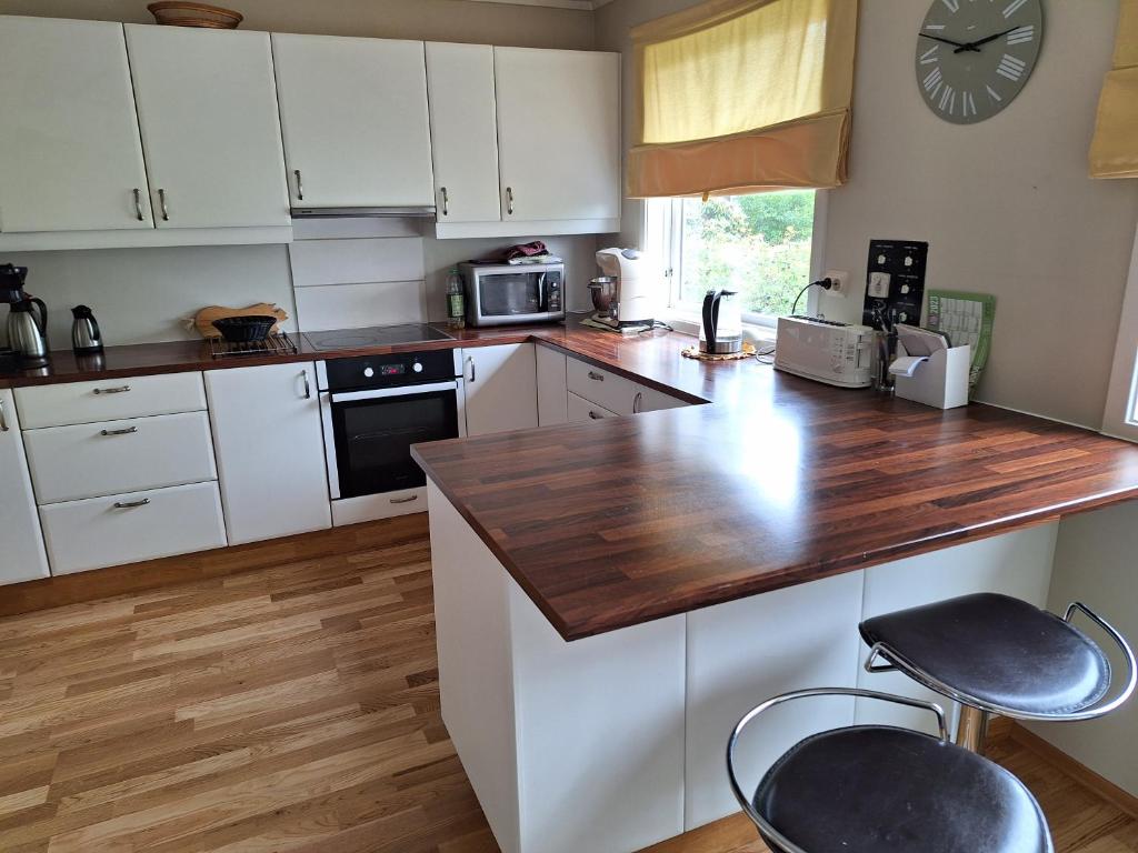 a kitchen with white cabinets and a wooden counter top at Stemmen 16 in Bryne