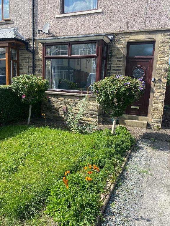 a house with a yard with flowers in front of it at Huddersfield 2 bedroom house in Huddersfield