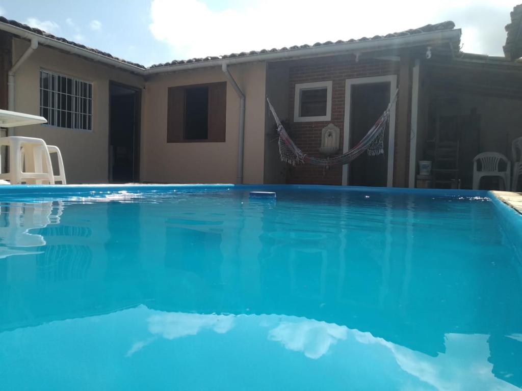 a swimming pool in front of a house at Casinha Sossego na Praia in Caraguatatuba