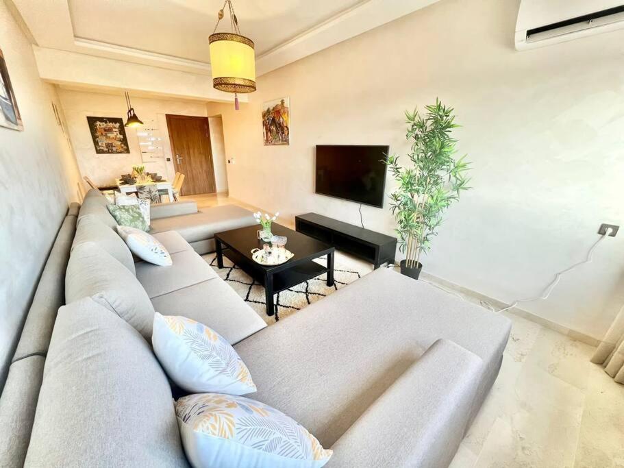 - un salon avec un canapé et une télévision dans l'établissement Cozy&Elegant apartment/pool/city center/Gueliz, à Marrakech