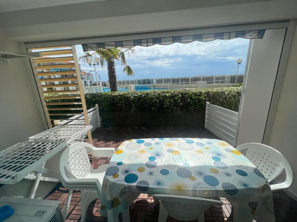 un patio avec une table et des chaises sur un balcon dans l'établissement T3 front de mer avec piscine, à Frontignan