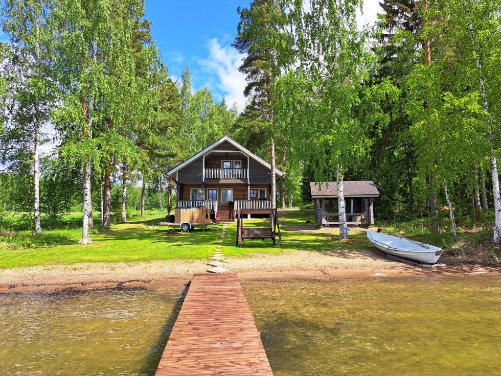 une maison sur la rive d'un lac avec un bateau dans l'établissement Kurkimökki, à Parikkala