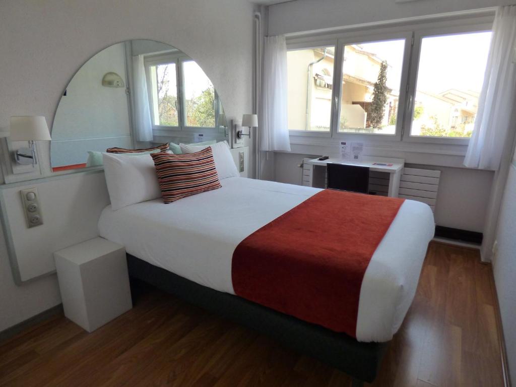 マコンにあるCit'Hotel Escatelのベッドルーム(大型ベッド1台、鏡付)