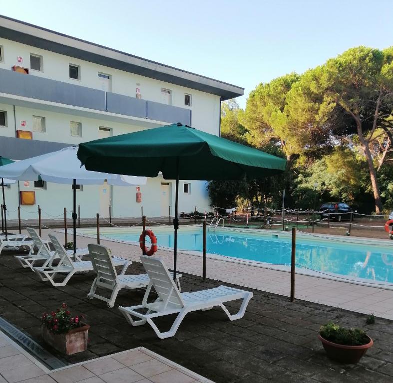 un gruppo di sedie e un ombrellone accanto alla piscina di Residence Verde Pineta a Principina a Mare