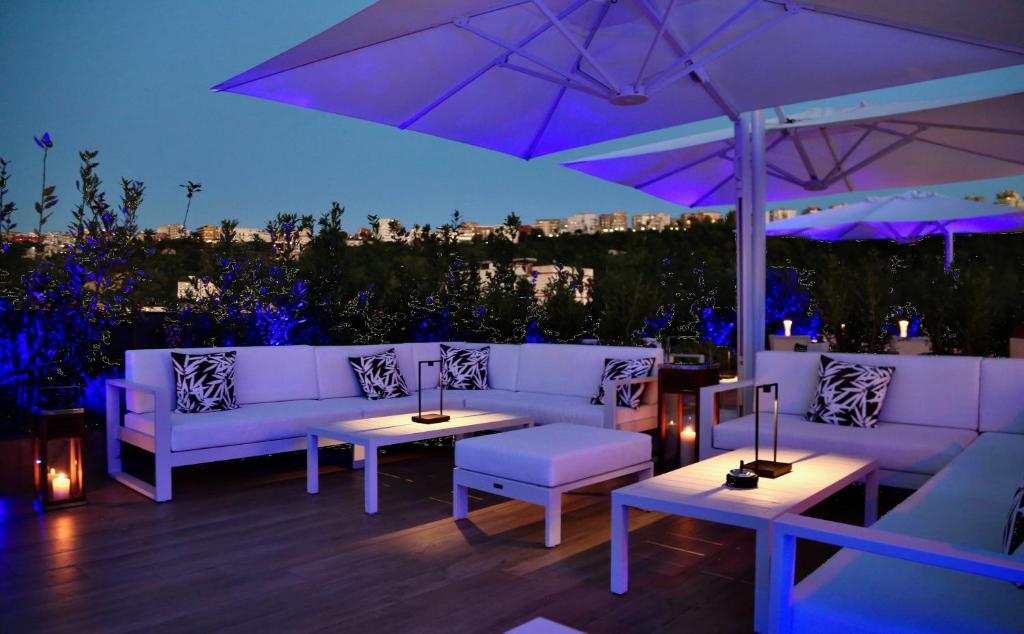 a patio with white couches and tables and an umbrella at LHP Napoli Palace & SPA in Naples
