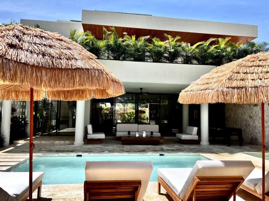 um resort com uma piscina com cadeiras e guarda-sóis em Kaikai Beach House, un lujo en el Caribe em Las Terrenas