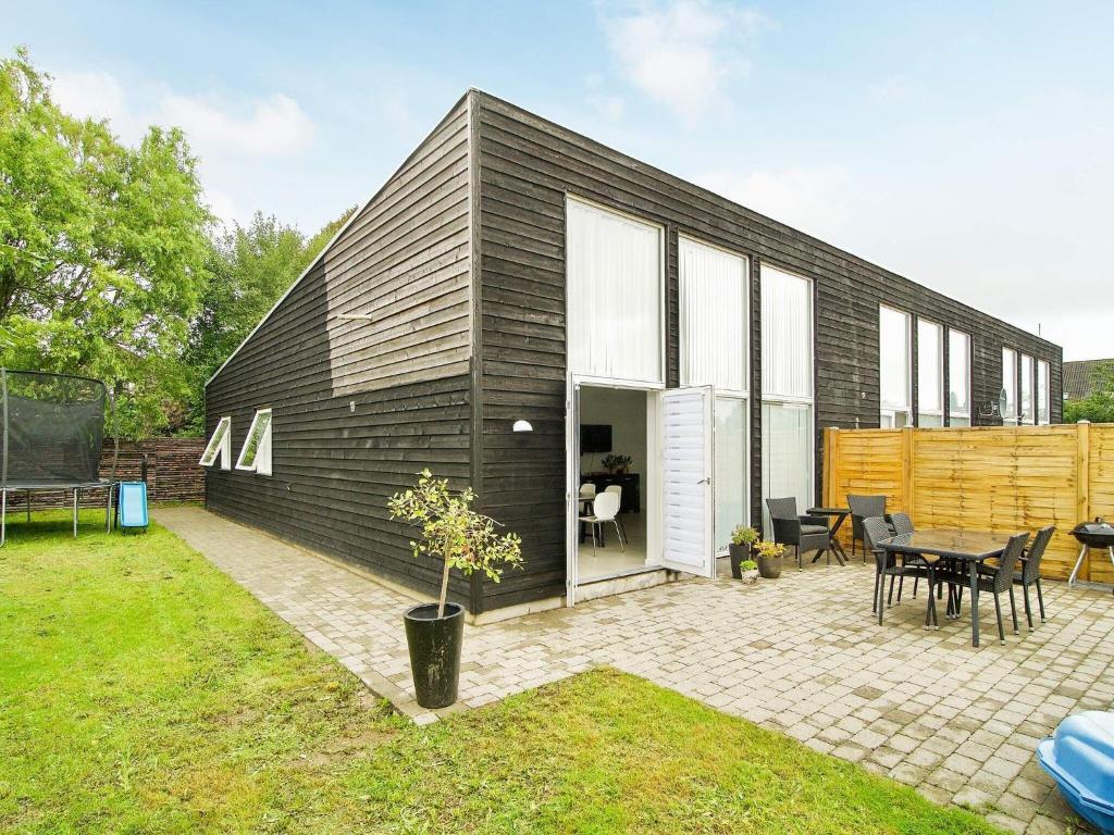 a black house with a patio and a table at Holiday home Gilleleje CVII in Gilleleje