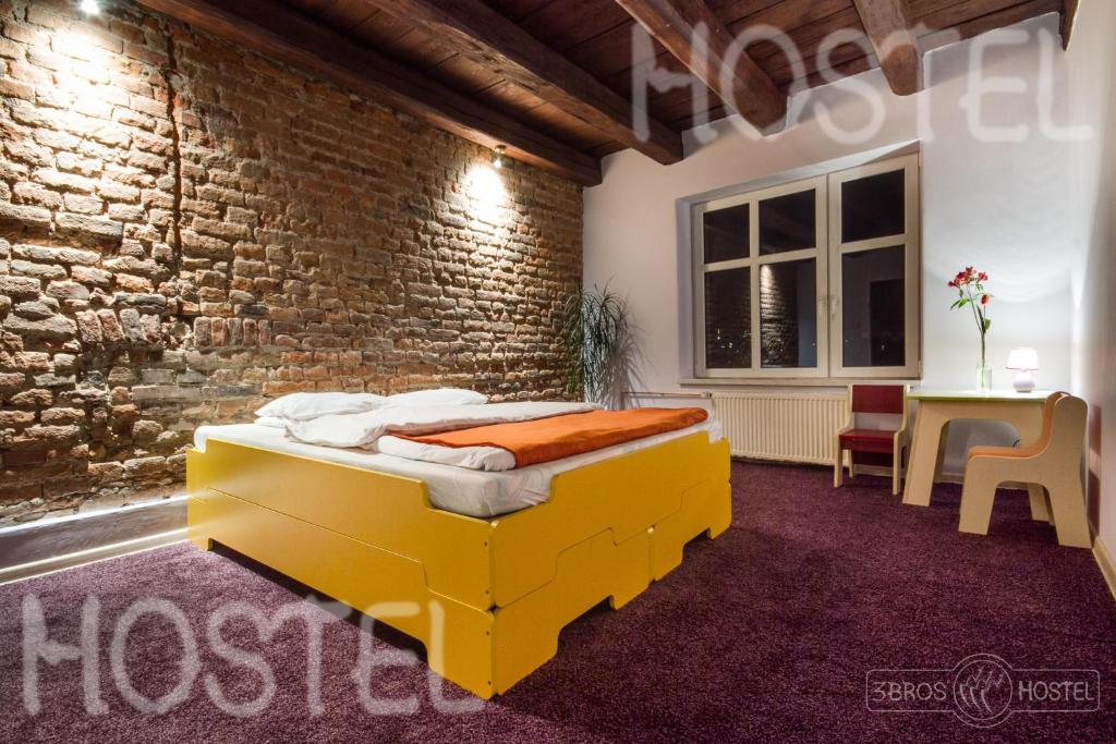 Un dormitorio con una cama amarilla en una pared de ladrillo en 3 Bros' Hostel Cieszyn en Cieszyn