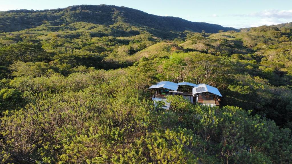 z góry widok na dom na szczycie wzgórza w obiekcie Four Trees Jungle Lodge w mieście San Juan del Sur