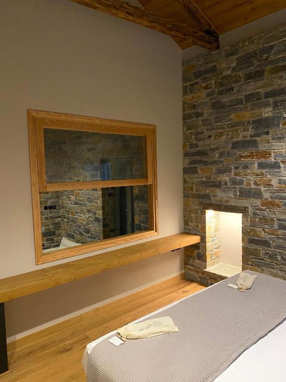 a bedroom with a brick wall and a bed and a window at EJ Boutique Suites in Milina