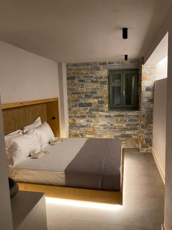 a bedroom with a bed and a brick wall at EJ Boutique Suites in Milina