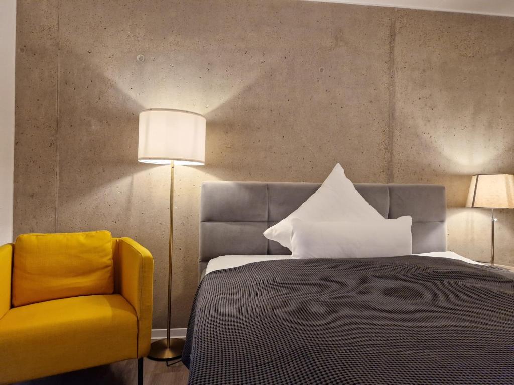 1 dormitorio con 1 cama y 1 silla amarilla en Urban City Lifestyle Appartement en Bielefeld