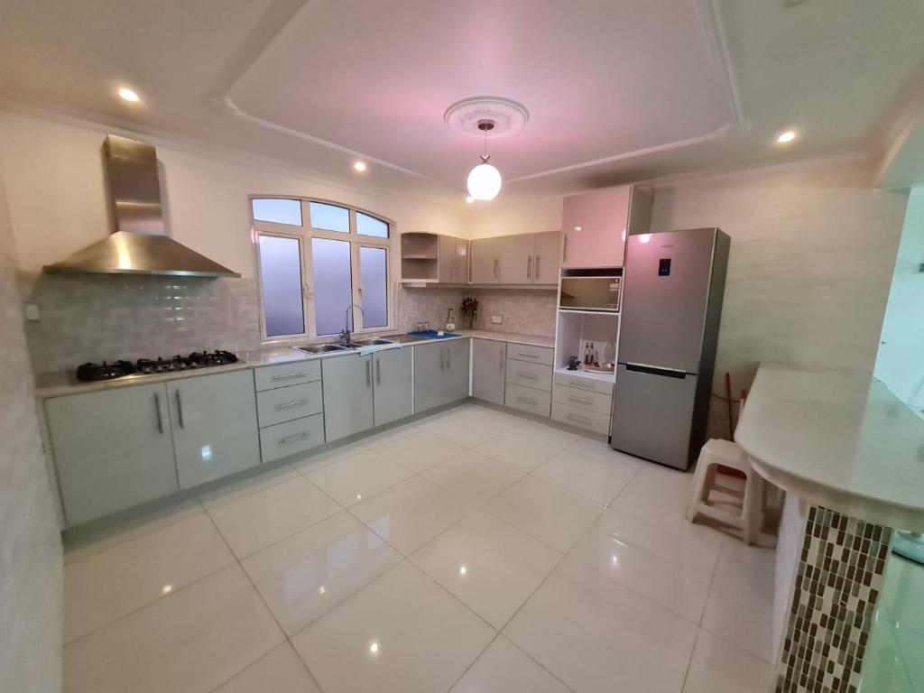 cocina grande con armarios blancos y nevera en White Residence en Quatre Bornes