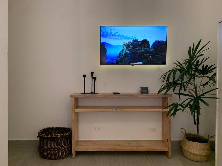 a tv hanging on a wall above a shelf with a plant at Cozy Apartment at The Village in Punta Cana