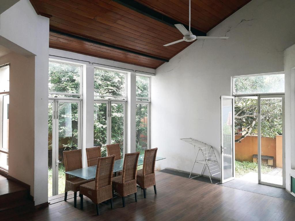 een eetkamer met een tafel, stoelen en ramen bij Mango Tree Villa in Sri Jayewardenepura Kotte