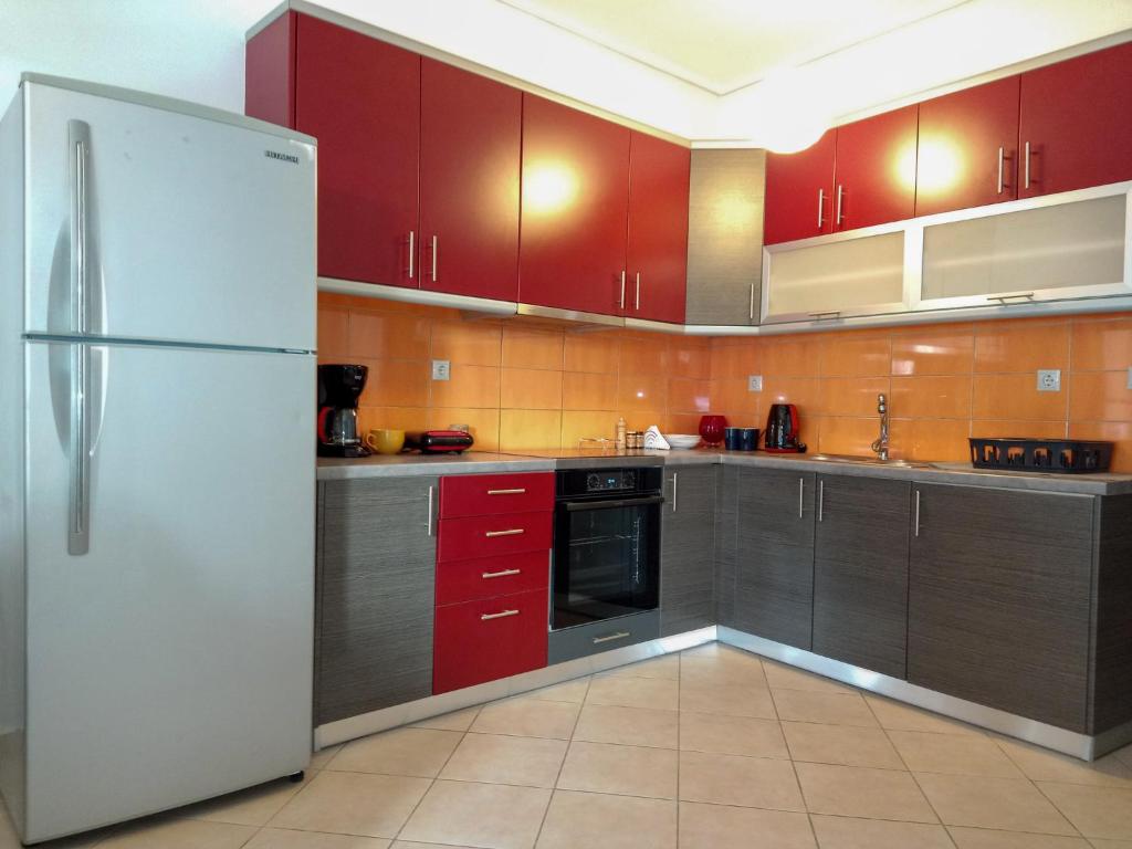 eine Küche mit roten Schränken und einem Kühlschrank in der Unterkunft Ιδανικό διαμέρισμα δίπλα στο μετρό, ανάμεσα στο κέντρο και τη παραλία in Athen