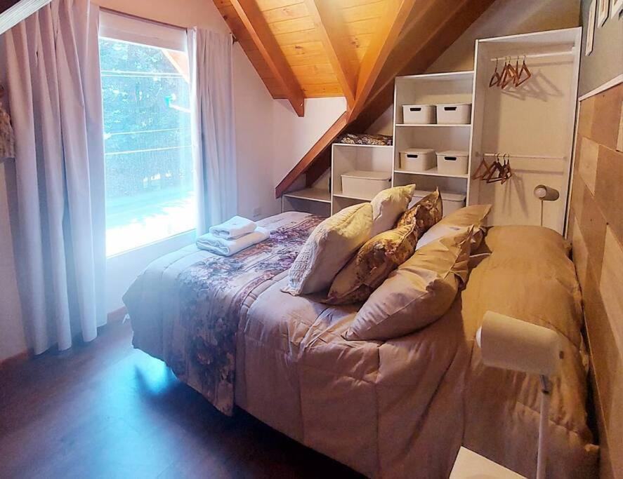 1 dormitorio con cama con almohadas y ventana en Amutuy Bariloche en San Carlos de Bariloche