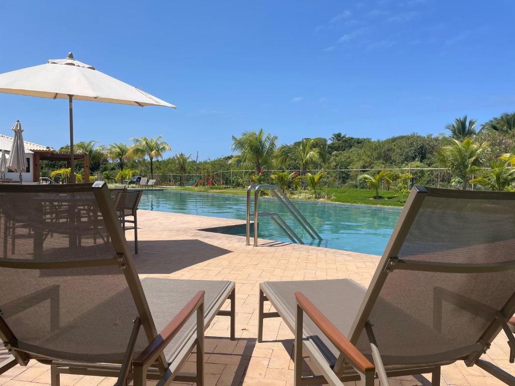 a patio with chairs and an umbrella next to a pool at INCRIVEL apartamento com vista lago! in Praia do Forte