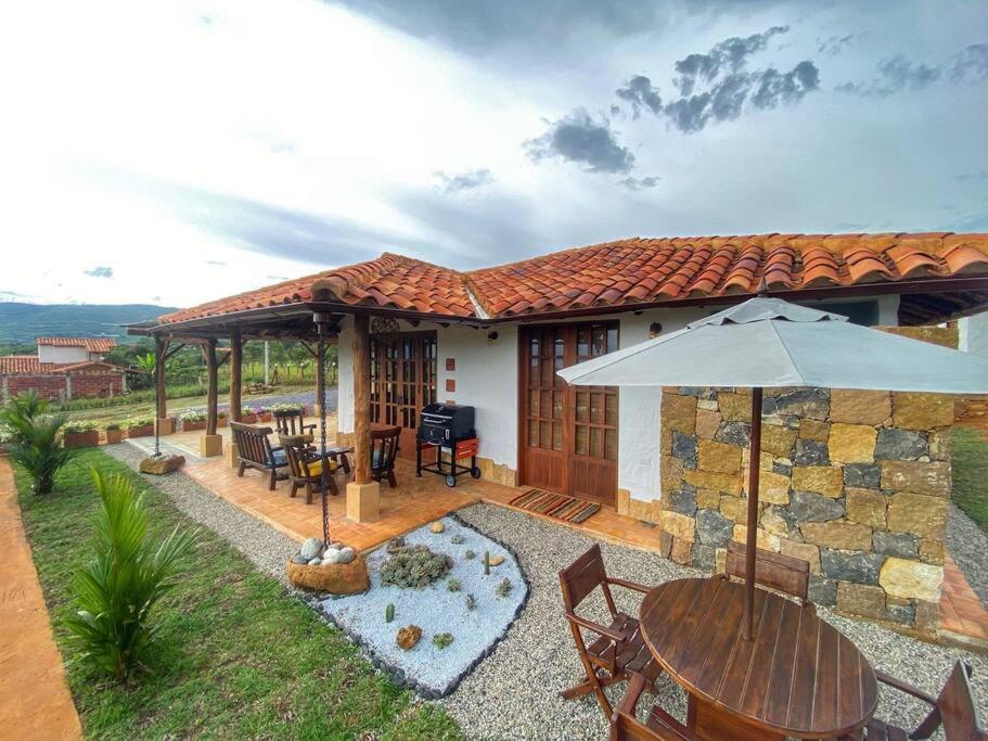 una casa con patio con tavolo e ombrellone di Cabaña Villa Chelita descanso y confort. a Barichara
