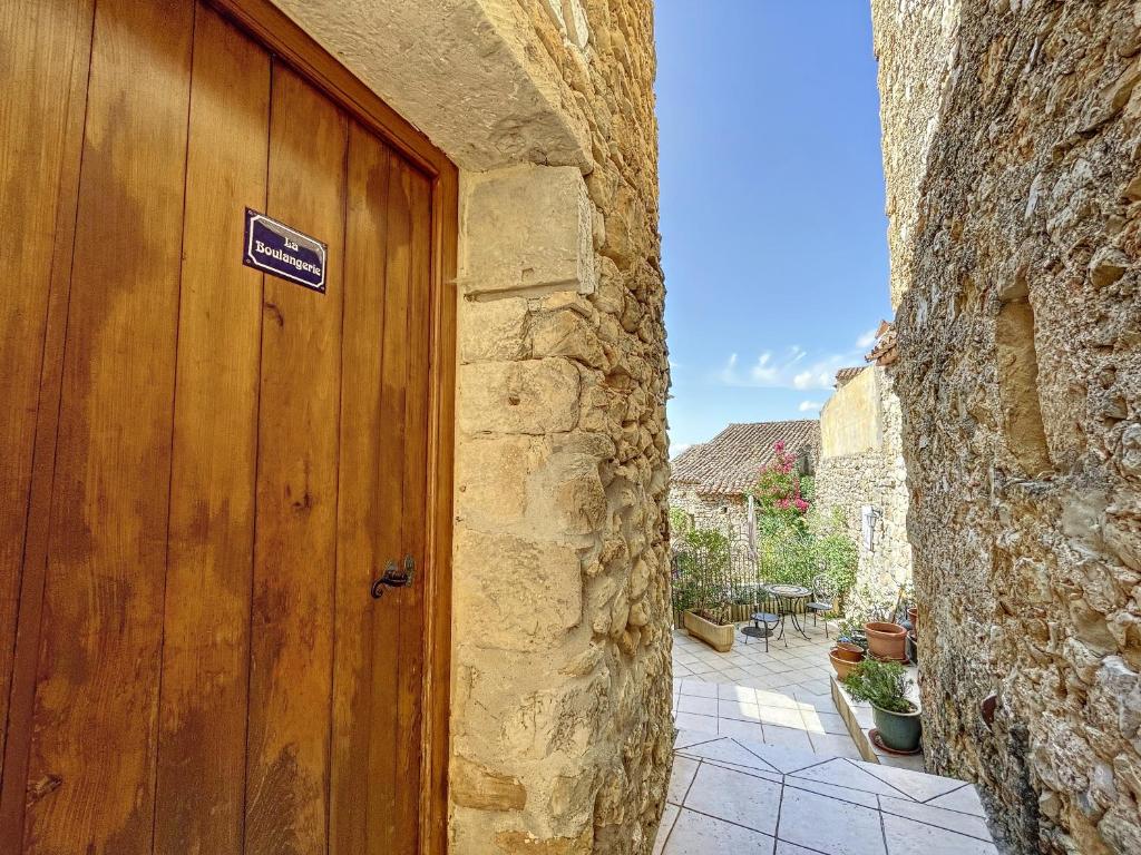 a wooden door in a stone building with a sign on it at LA BOULANGERIE in Saint-Sauveur-de-Cruzières