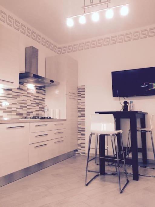 a kitchen with a table and a tv on a wall at Royal Apartment in Ciampino