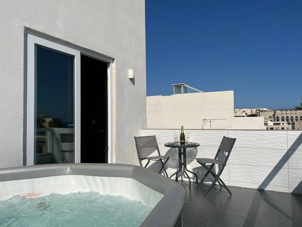 Luxury Penthouse in Sliema في سليمة: حوض استحمام على شرفة مع طاولة وكراسي