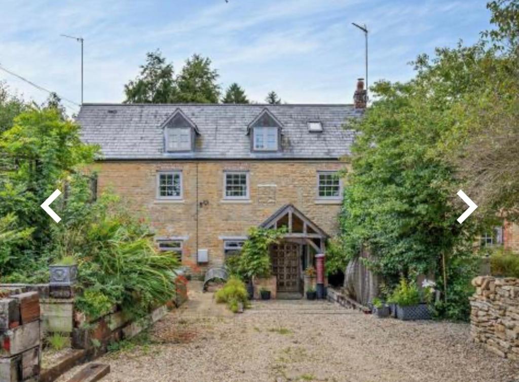 uma grande casa de tijolos com duas setas apontadas para a frente em Luxury Country Cottage With A View em Enstone